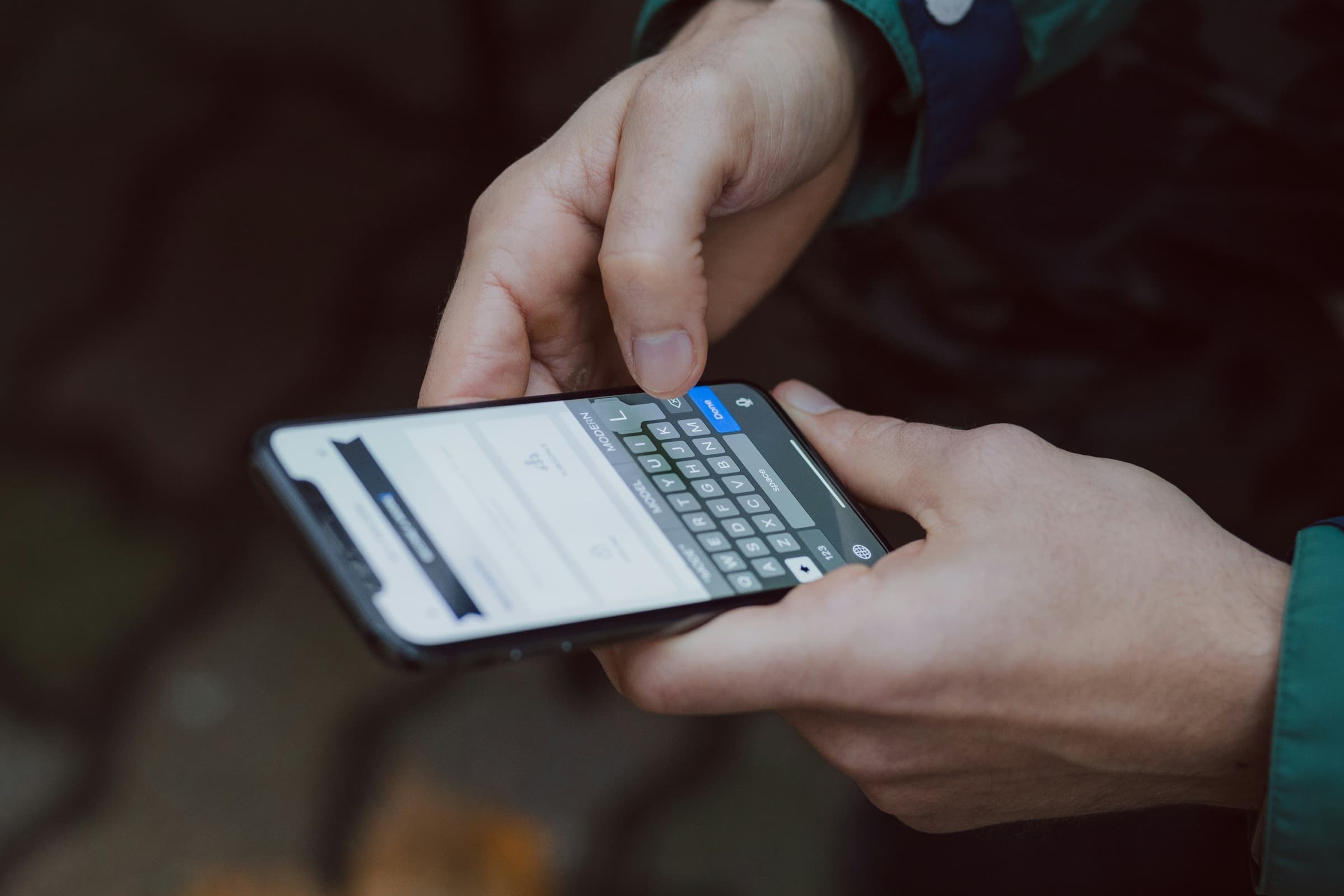 Two hands typing on a smartphone keyboard