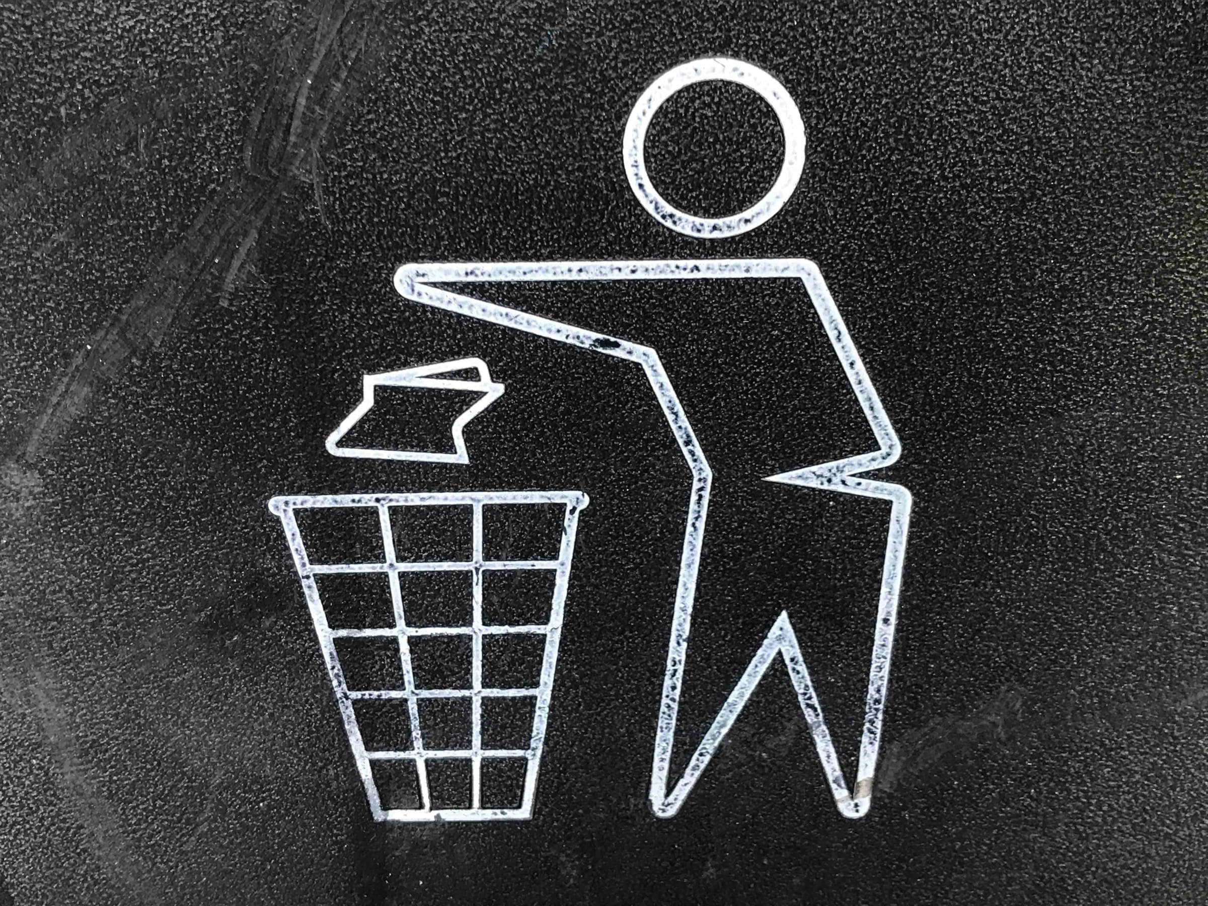 A white bin symbol painted on black asphalt