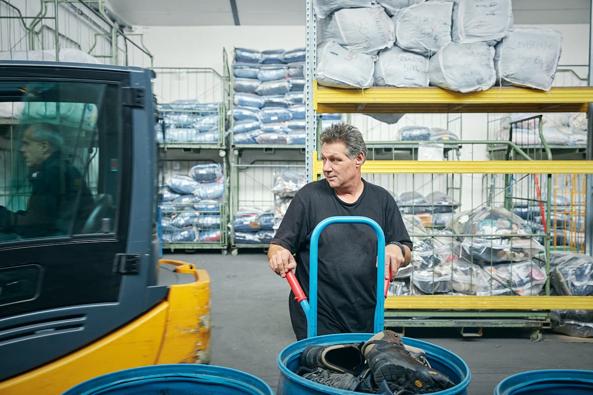 A worker moving donated clothing through the sorting warehouse