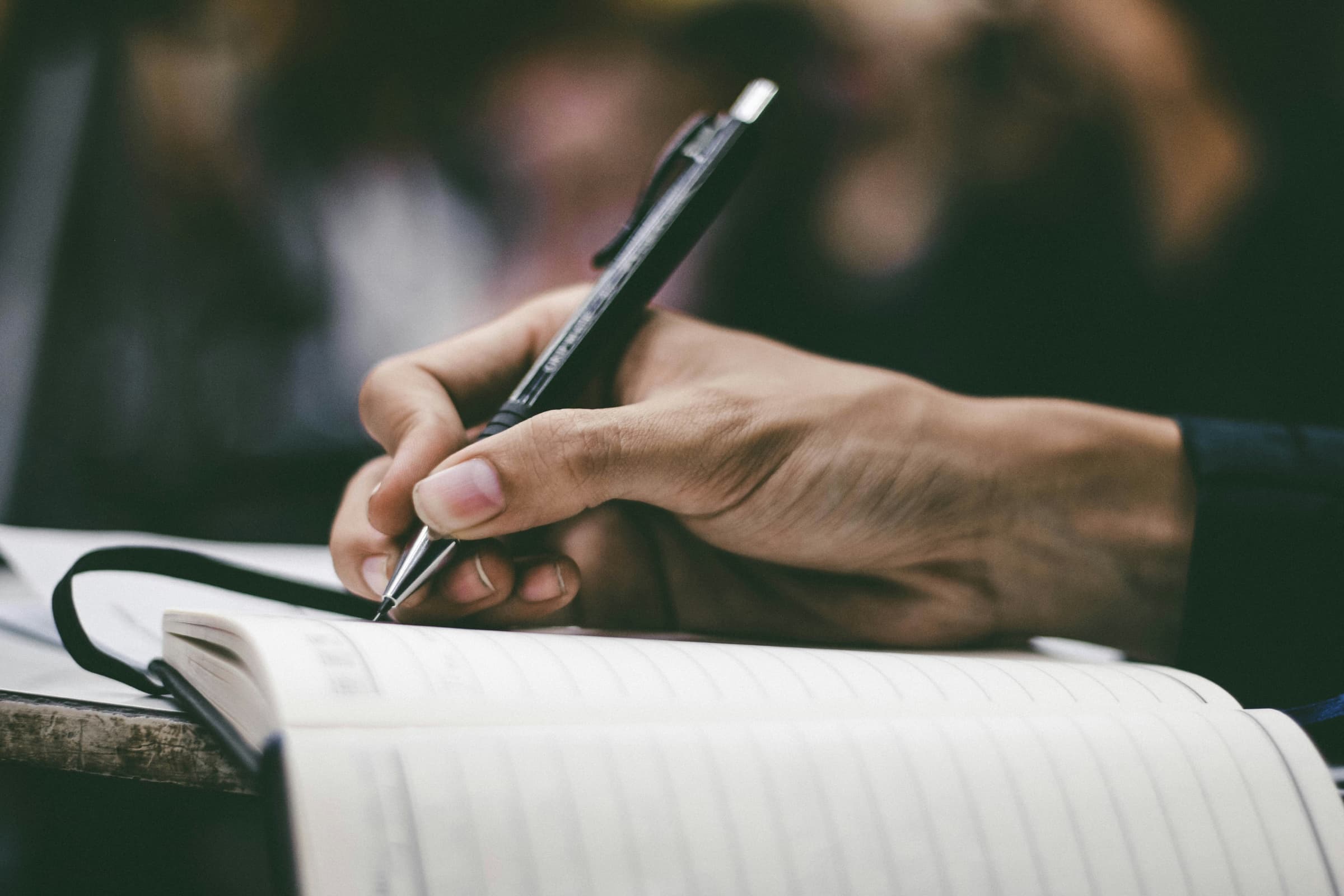A hand writing in a notebook with a black pen