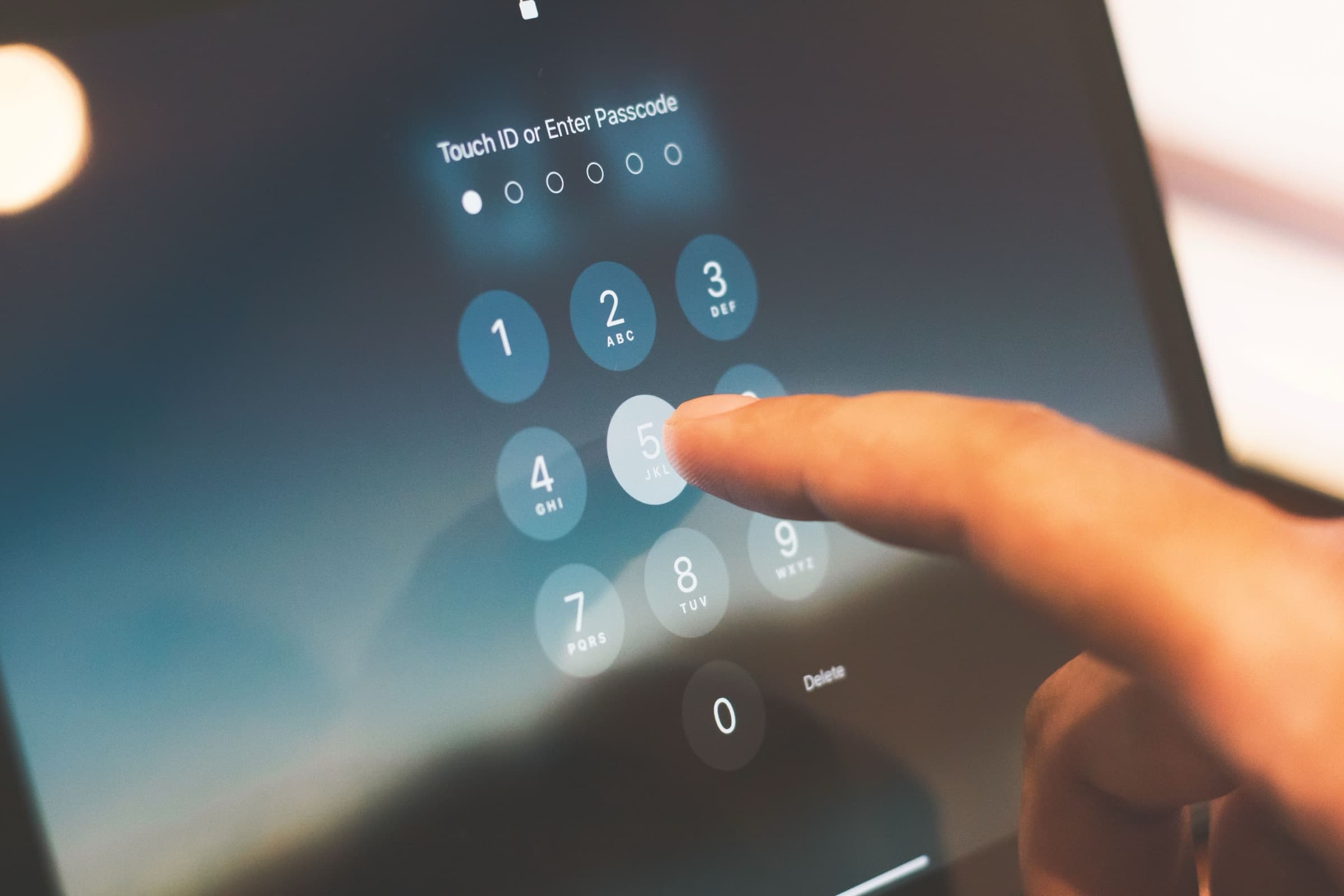 A finger entering a passcode on a tablet lock screen