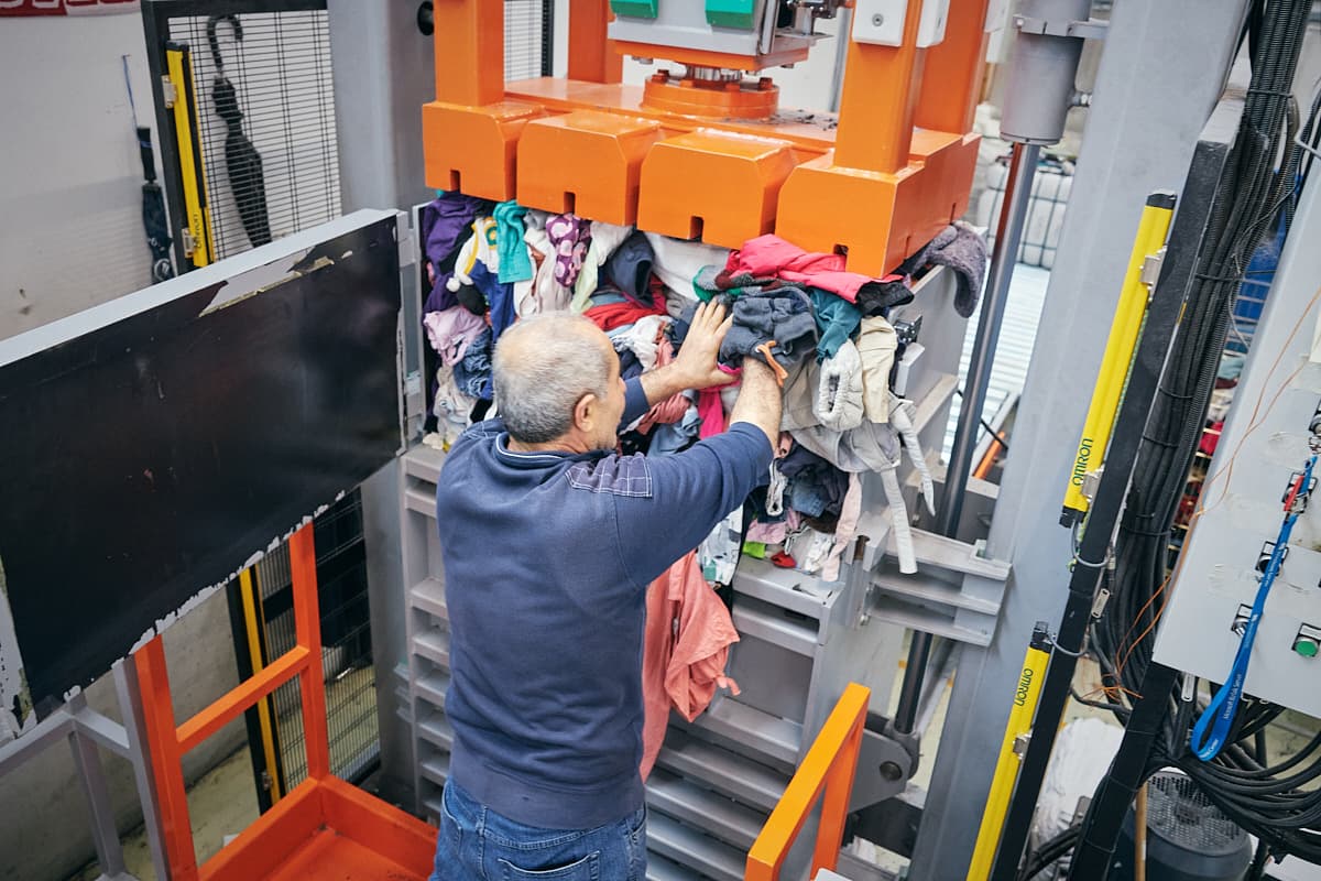 A worker operating the baling press at the sorting facility