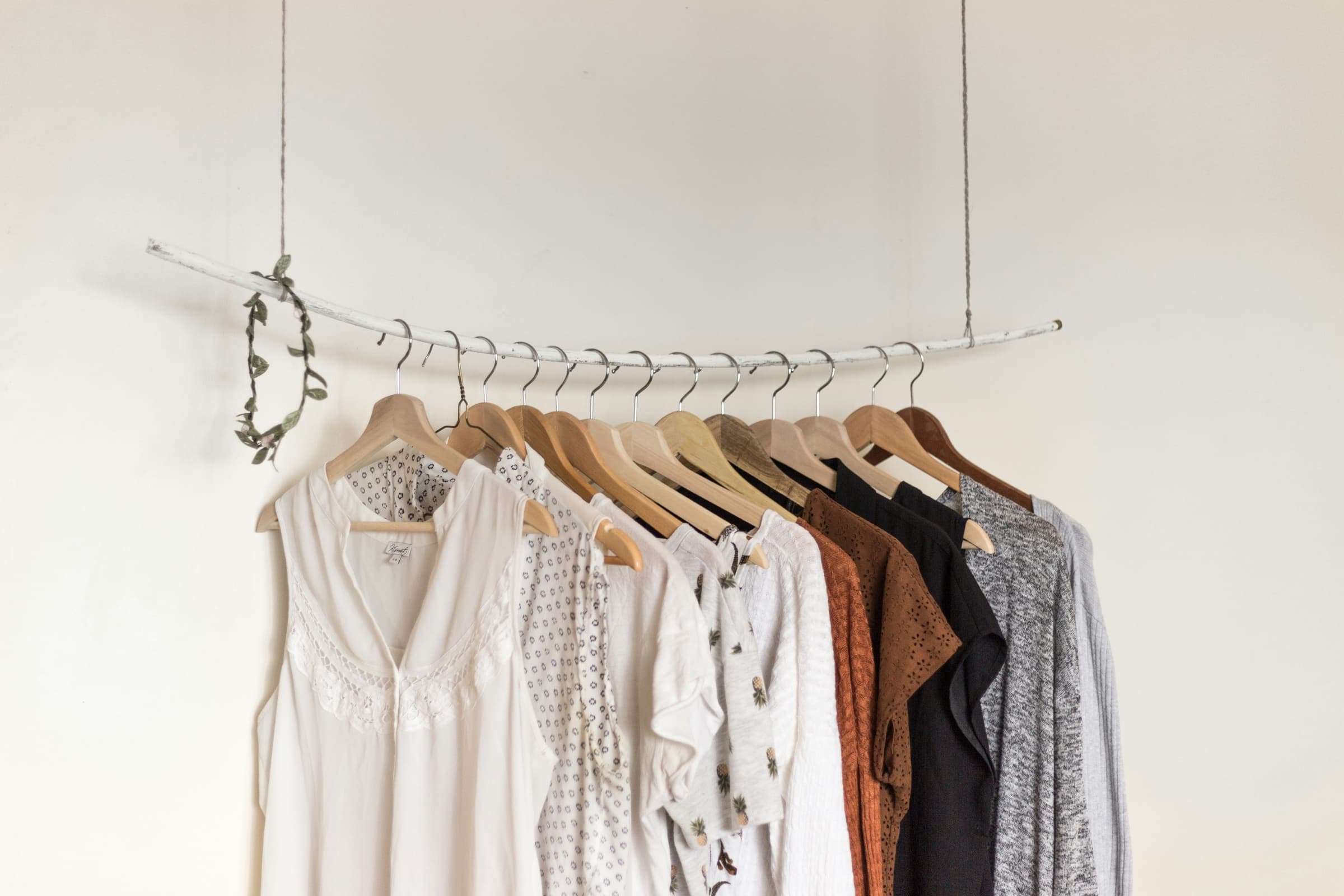 A few blouses and knits in neutral colours on a hanging clothes rail